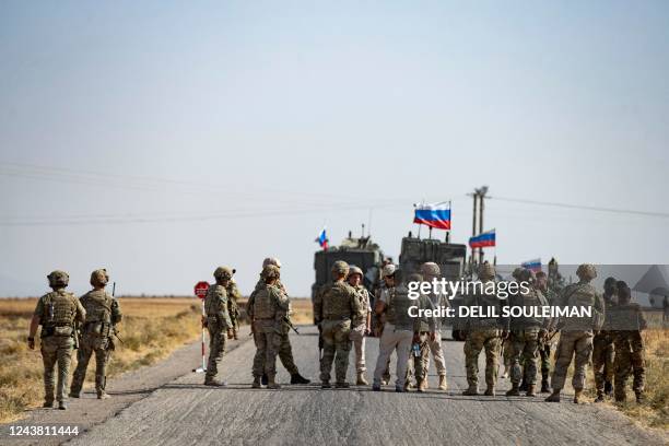 Soldiers of a Russian military convoy and their US counterparts exchange greetings as their patrol routes intersect in an oil field near Syria's...