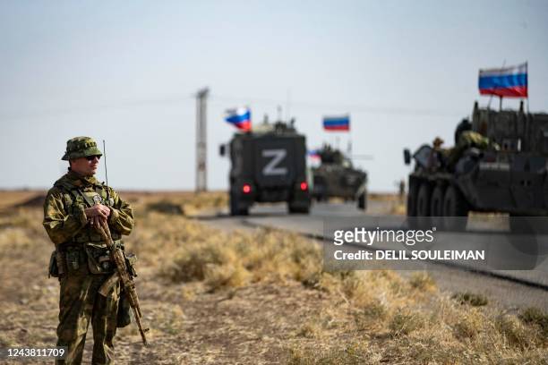 Soldiers of a Russian military convoy and their US counterparts exchange greetings as their patrol routes intersect in an oil field near Syria's...