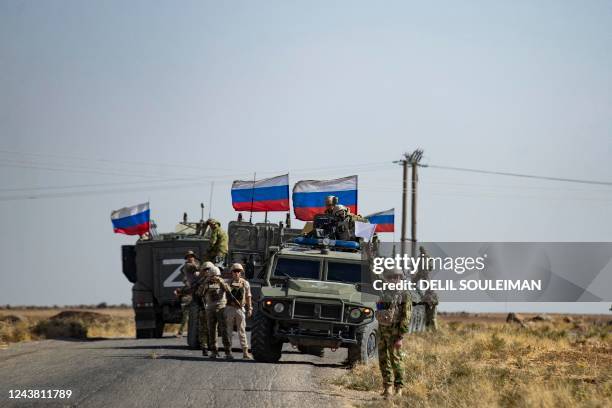 Soldiers of a Russian military convoy and their US counterparts exchange greetings as their patrol routes intersect in an oil field near Syria's...