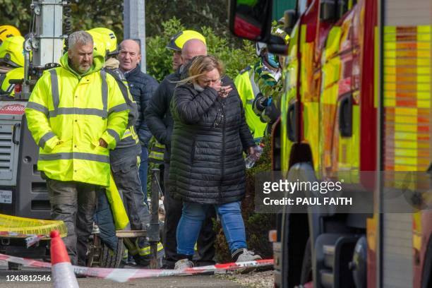 Woman holding rosary beads reacts inside the cordon as emergency services attend the scene following an explosion in Creeslough, in the north west of...