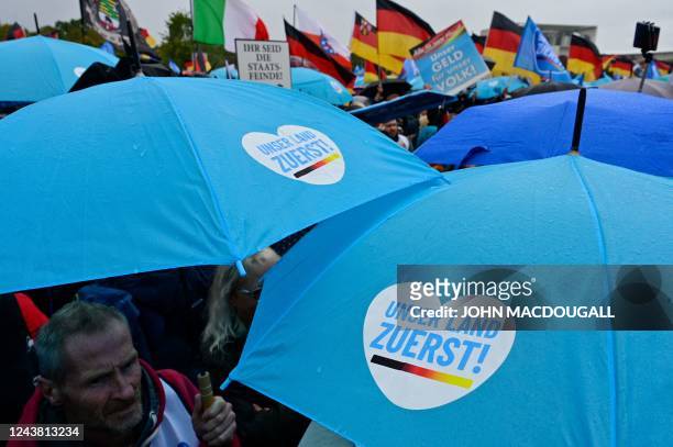 Protesters shelter under umbrellas with "Our country first" written on it during a rally of far-right groups including the Alternative for Germany...
