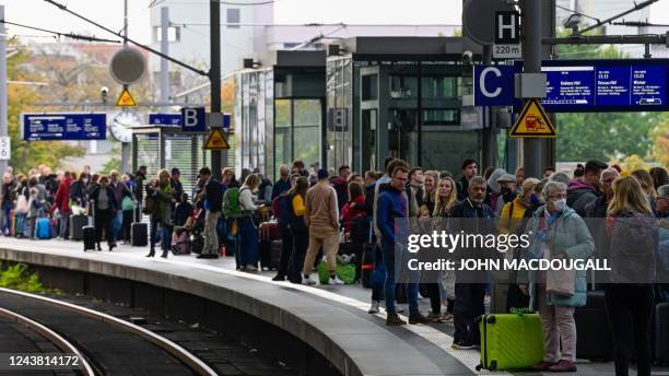 Rail passengers wait for a train on a platform at the main train station in Berlin on October 8, 2022 following major disruption on the German...