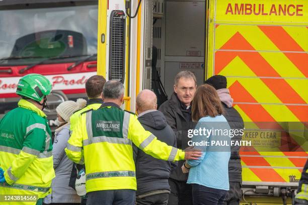 Priest comforts people by an ambulance as emergency services attend the scene following an explosion in Creeslough, in the north west of Ireland on...