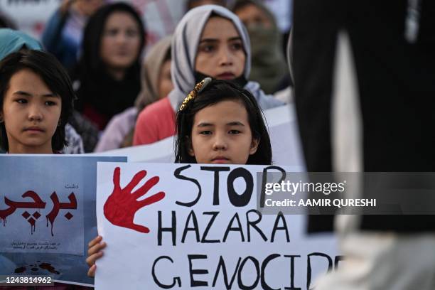 Members of the Afghan Hazara community hold placards during a protest against the suicide bombing at a university in Afghanistan on September 30, in...