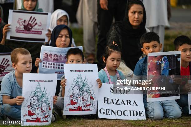 Members of the Afghan Hazara community hold placards during a protest against the suicide bombing at a university in Afghanistan on September 30, in...
