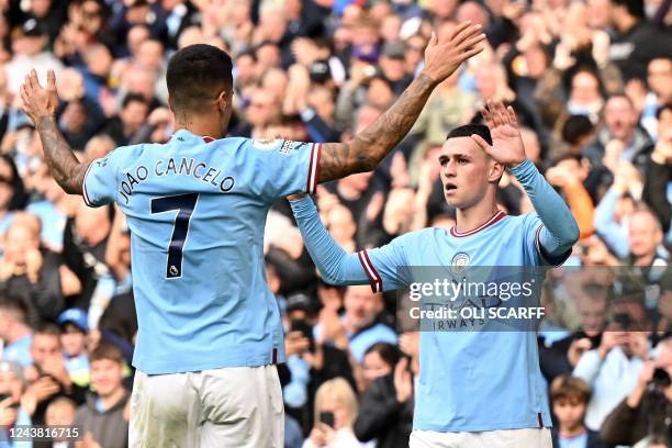 Manchester City's English midfielder Phil Foden celebrates scoring the team's second goal with Manchester City's Portuguese defender Joao Cancelo...