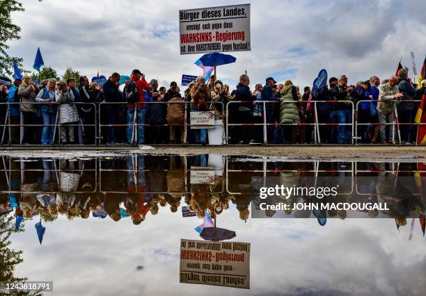 Protesters are reflected in rain water during a rally of far-right groups including the Alternative for Germany party against rising prices in Berlin...