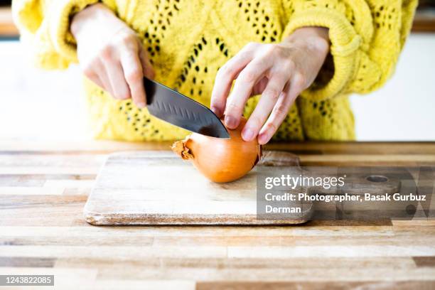 a woman chopping onions with a kitchen knife on wooden cutting board - cebola imagens e fotografias de stock