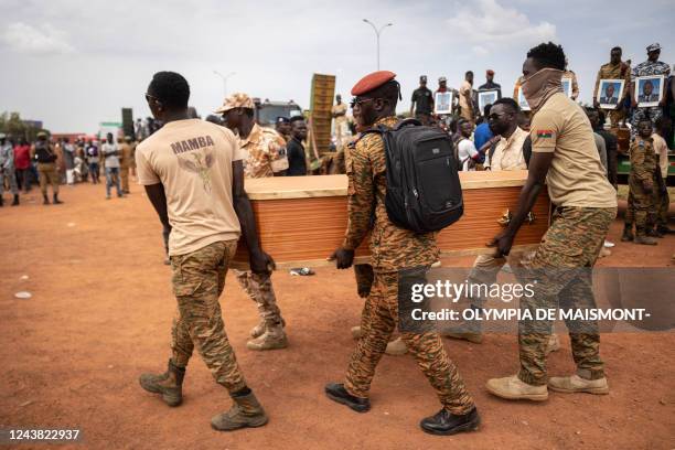 Burkina Faso's servicemen carry a coffin during the burial of the 27 soldiers killed as they escorted 207-vehicles in a convoy in Gaskinde, during...