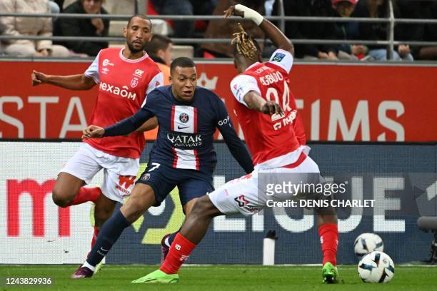 Reims' Moroccan defender Yunis Abdelhamid fights for the ball with Paris Saint-Germain's French forward Kylian Mbappe and Reims' Ivorian defender...