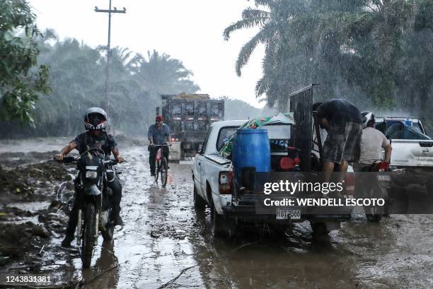 Residents leave their house under pouring rain at the former banana fields of the municipality of El Progreso, Yoro department, Honduras, before the...