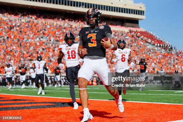 Quarterback Spencer Sanders of the Oklahoma State Cowboys scores a touchdown on a 14-yard run against defensive back Tyler Owens and linebacker Kosi...