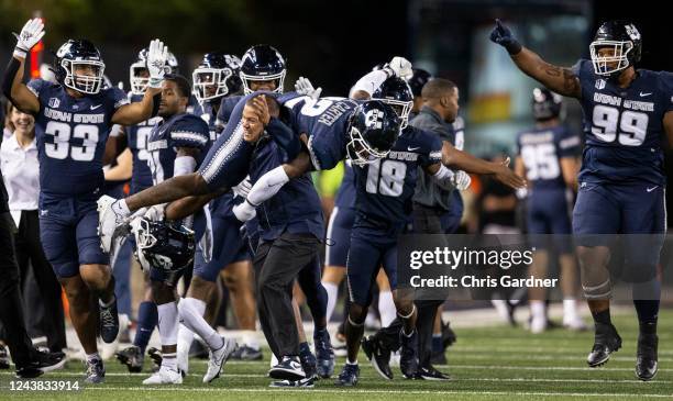 Defensive Coordinator Ephraim Banda carries Ajani Carter of the Utah State Aggies after he intercepted a pass in the endzone by the Air Force Falcons...