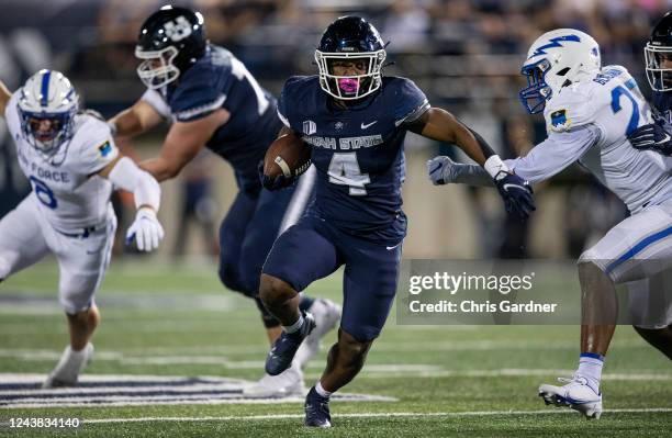 Calvin Tyler Jr., #4 of the Utah State Aggies rushes the ball against TD Blackmon and Bo Richter of the Air Force Falcons during the second half of...