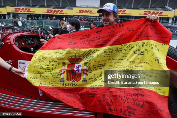 Fernando Alonso of Spain and Alpine F1 team poses for photo with national flag signed by fans and supporters during drivers parade prior to the F1...