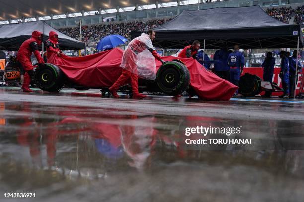 Ferrari's Spanish driver Carlos Sainz Jr's damaged car is moved through the pit lane during the Formula One Japanese Grand Prix at Suzuka, Mie...