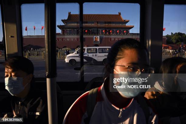 Passengers on a bus look on as they drive past the Tiananmen Gate in Beijing on October 9, 2022.