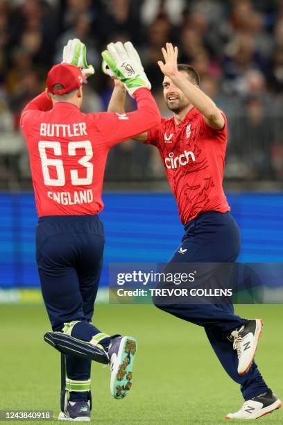 England Jos Buttler and Mark Wood celebrate the dismissal of Australia's Tim David during the first cricket match of the Twenty20 series between...