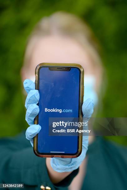 In this photo illustration, A woman wearing a protective face mask is holding an iPhone showing the app of booking.com on June 1, 2020 in Veghel,...