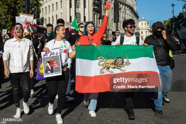 Protesters holding Iranian flags and images of Mahsa Amini and with hands daubed with fake blood march from Trafalgar Square to Parliament Square in...