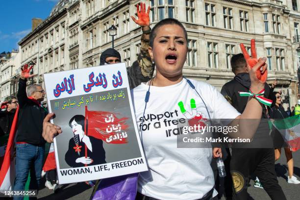 Protesters holding Iranian flags and images of Mahsa Amini and with hands daubed with fake blood march from Trafalgar Square to Parliament Square in...