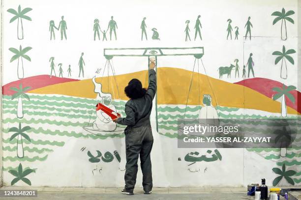 Graffiti artist Dana al-Mekaimi paints a mural dedicated to women's empowerment with a slogan reading in Arabic 'you first' at Kuwait Times newspaper...