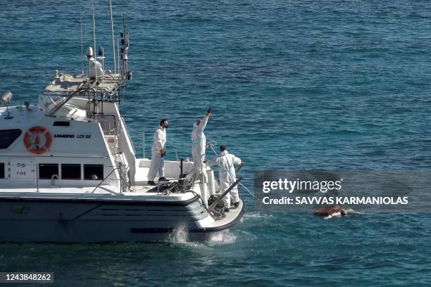 Graphic content / TOPSHOT - Greek coastguard rescuers recover a body from the sea off the island of Kythira, at the southern end of the Peloponnese...