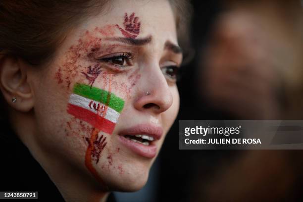 Demonstrator with an Iranian flag and red hands painted on her face attends a rally in support of Iranian protests, in Paris on October 9 following...