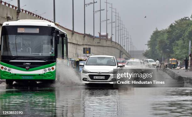 Commuters wade through a waterlogged road in rain at NH-24 near IP Extension, on October 9, 2022 in New Delhi, India. Heavy rains are lashing parts...
