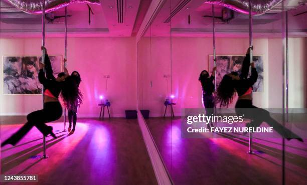 Saudi yoga instructor Nada, and another woman exercise by pole dancing at a local gymnasium in the capital Riyadh, on October 1, 2022. - When Nada...