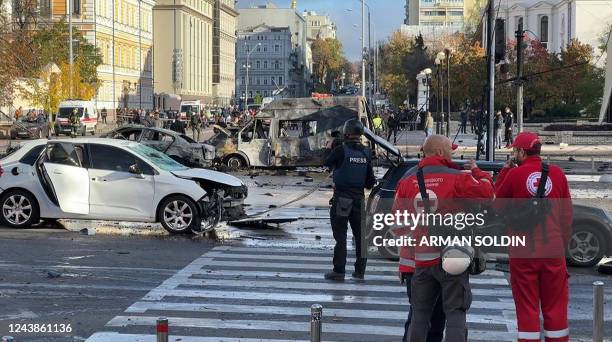 This video grab taken from an AFPTV footage shows vehicles destroyed in Kyiv on October 10, 2022 as security and emergency forces work on the scene...