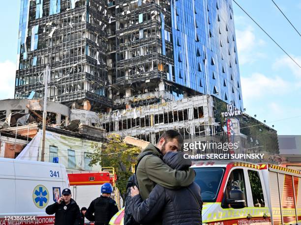 People react outside a partially destroyed multistorey office building after several Russian strikes hit the Ukrainian capital of Kyiv on October 10...