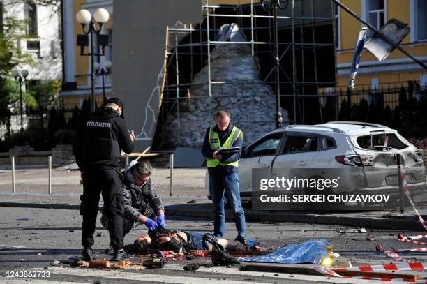 Graphic content / TOPSHOT - Police experts examine a body in the center of Ukrainian capital of Kyiv after a missile strike on October 10, 2022. -...