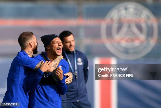 Paris Saint-Germain's Spanish defender Sergio Ramos jokes with Paris Saint-Germain's French forward Kylian Mbappe during a training session at the...