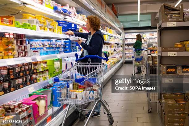 Woman seen picking products from an Aldi supermarket refrigerator while grocery shopping. Inflation in Spain and Europe reached a record high of 10%...