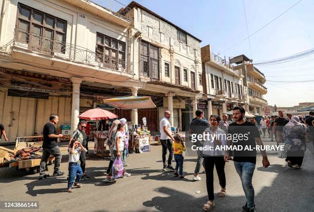 People walk along al-Mutanabbi street in the centre of Iraq's capital Baghdad on October 7, 2022. - A year since Iraq's last elections, it remains...