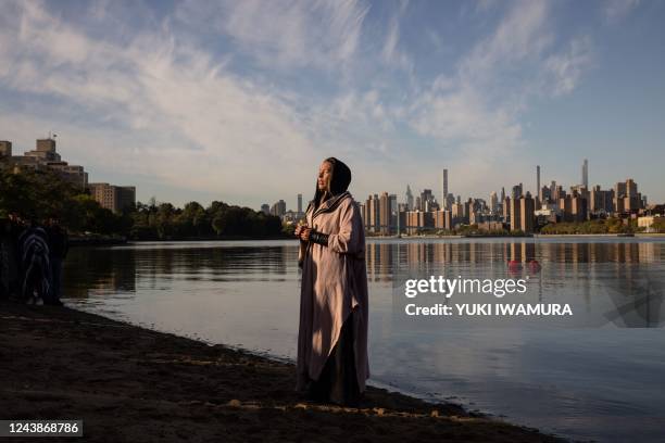 Woman prays while holding a container of water brought from Puerto Rico during an Indigenous Peoples' Day sunrise ceremony on Randall's Island in New...