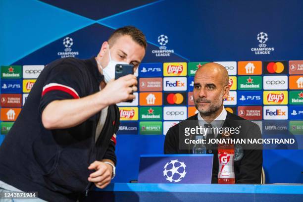 Fans takes a selfie with Manchester City's Spanish manager Pep Guardiola as he attends a press conference at Parken stadium in Copenhagen, Denmark,...