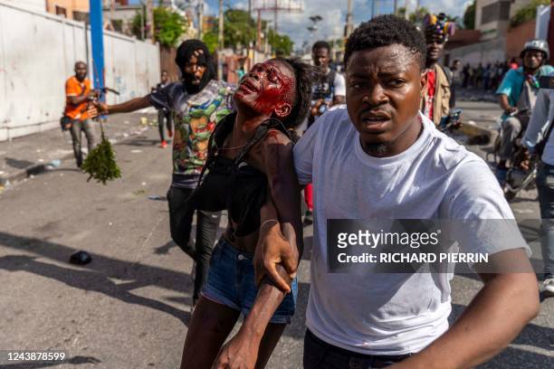 Man assists an injured woman during a protest against Haitian Prime Minister Ariel Henry calling for his resignation, in Port-au-Prince, Haiti,...