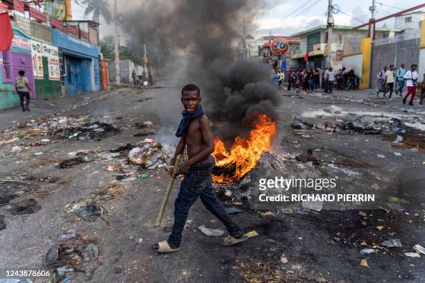 Mans walks past a burning barricade during a protest against Haitian Prime Minister Ariel Henry calling for his resignation, in Port-au-Prince,...