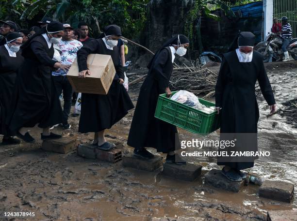 Nuns cross over stones carring humanitarian aid to be distributed among the victims of the landslide in Las Tejerias, Aragua state, Venezuela, on...