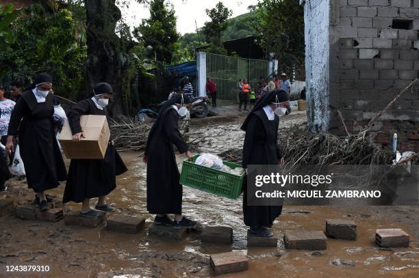 Nuns cross over stones carring humanitarian aid to be distributed among the victims of the landslide in Las Tejerias, Aragua state, Venezuela, on...