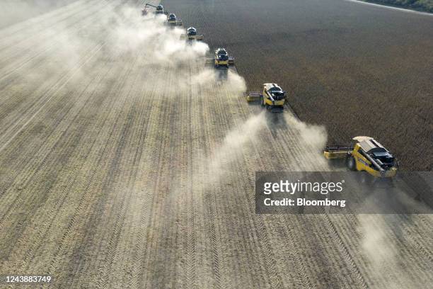 Combine harvesters cut through a field of soybean plants during the harvest on a farm, operated by Al Dahra Agricultural Co., in Padinska Skela,...