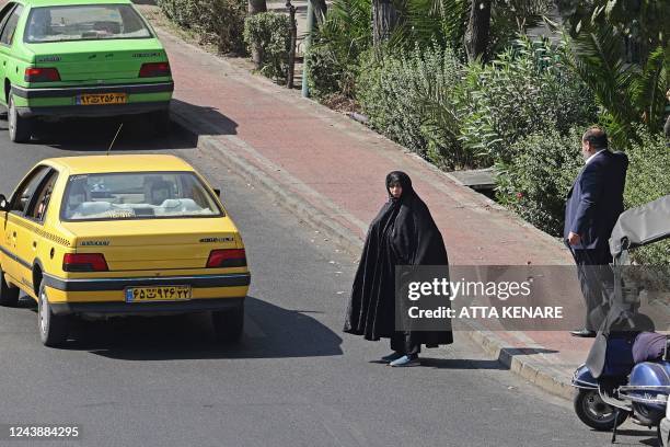 Woman waits to cross a street in the Iranian capital Tehran, on October 11, 2022.