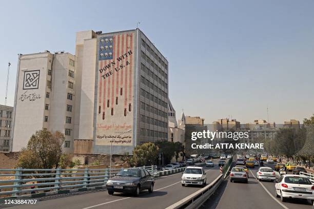 Vehicles drive past a landmark anti-US mural painted on the wall of a building on Karim Khan Zand Avenue in the Iranian capital Tehran, on October 11...