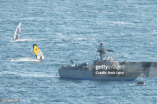 Wind surfers surf by an Israeli navy boat in the mediterranean sea at the Israeli side of the border with Lebanon on October 11, 2022 in Rosh...