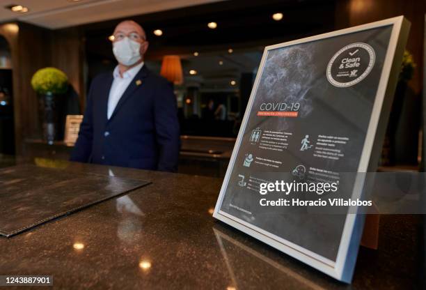 Staffer of five-star Grande Real Villa Itália Hotel & Spa wears protective mask as he stands behind the reception desk during a practice of working...