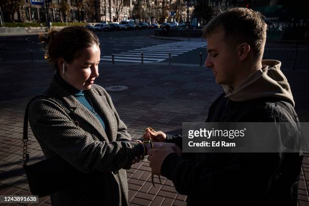 Man hands out blue and yellow ribbons on a shopping street on October 11, 2022 in Kyiv, Ukraine. Ukraine's emergency services said that 19 people...