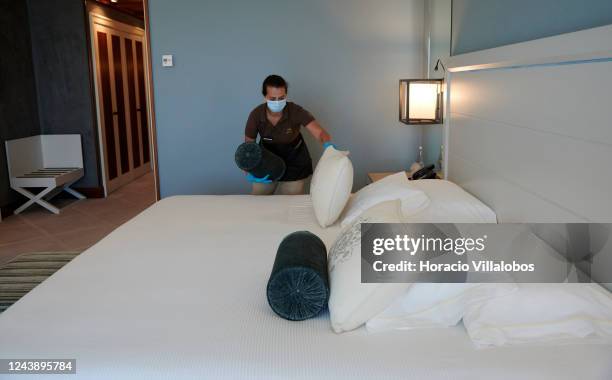 Staffer of five-star Grande Real Villa Itália Hotel & Spa wears protective mask and gloves as she opens the bed in a guest room during a practice of...