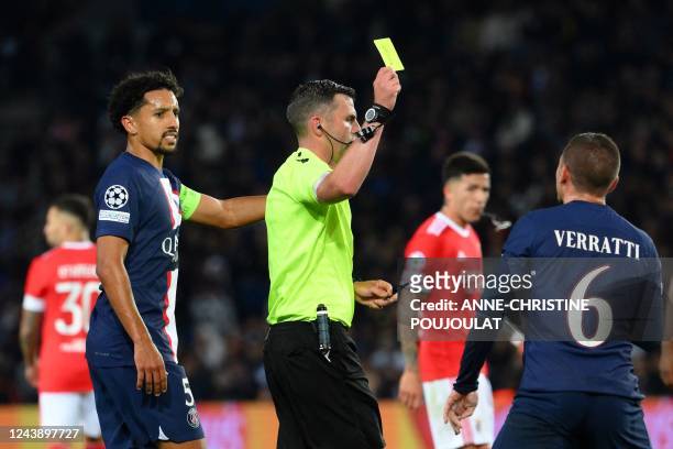 English referee Michael Oliver shows a yellow card to Paris Saint-Germain's Italian midfielder Marco Verratti during the UEFA Champions League group...